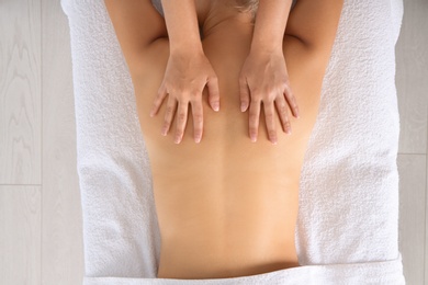 Photo of Relaxed woman receiving back massage in wellness center, top view