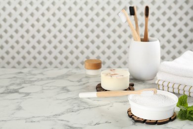 Photo of Composition with tooth powder and brushes on white marble table, space for text