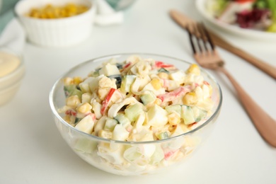 Photo of Delicious salad with crab sticks in glass bowl on white table