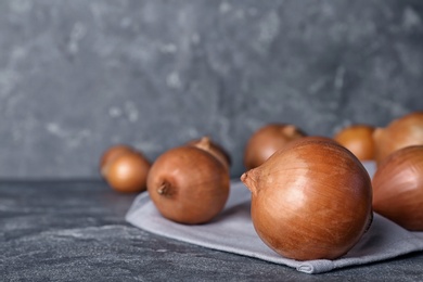 Photo of Fresh ripe onions on table against grey background