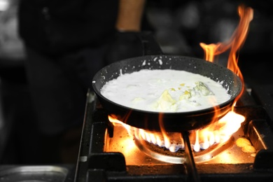 Photo of Frying pan with cheese and cream on stove