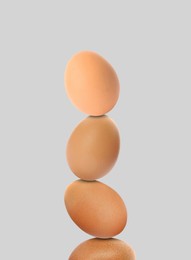 Image of Stacked fresh chicken eggs against light grey background