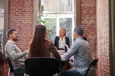 Photo of Businesswoman having meeting with her employees in office. Lady boss