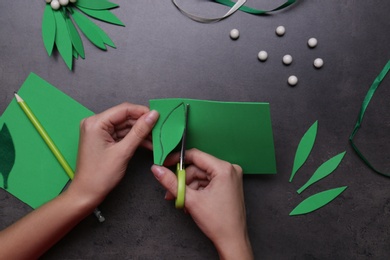 Photo of Woman making mistletoe branch on grey table, top view