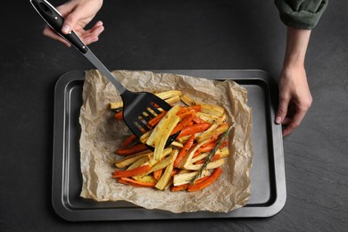 Photo of Cooker near baking pan with tasty parsnip and bell pepper at dark grey table, top view