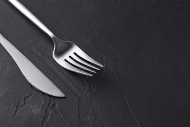 Photo of Beautiful cutlery set on black table, closeup. Space for text
