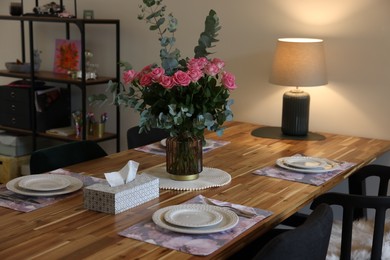 Photo of Beautiful table setting with bouquet and napkins indoors. Roses and eucalyptus branches in vase