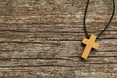 Photo of Christian cross on wooden table, top view. Space for text