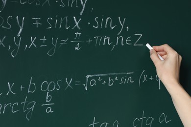 Photo of Teacher writing down math equation on green board, closeup