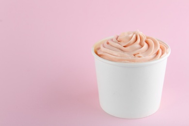 Photo of Cup with tasty frozen yogurt on pink background. Space for text