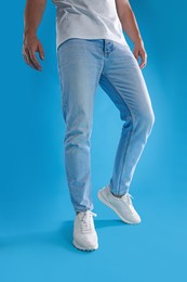 Photo of Man wearing stylish sneakers on light blue background, closeup