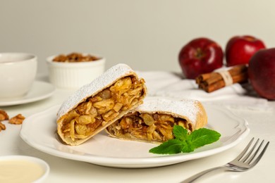 Photo of Delicious strudel with apples, nuts and raisins on white table, closeup