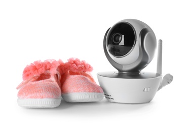Photo of Modern CCTV security camera and baby shoes on white background