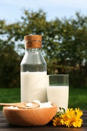 Photo of Tasty fresh milk and cottage cheese on wooden table outdoors