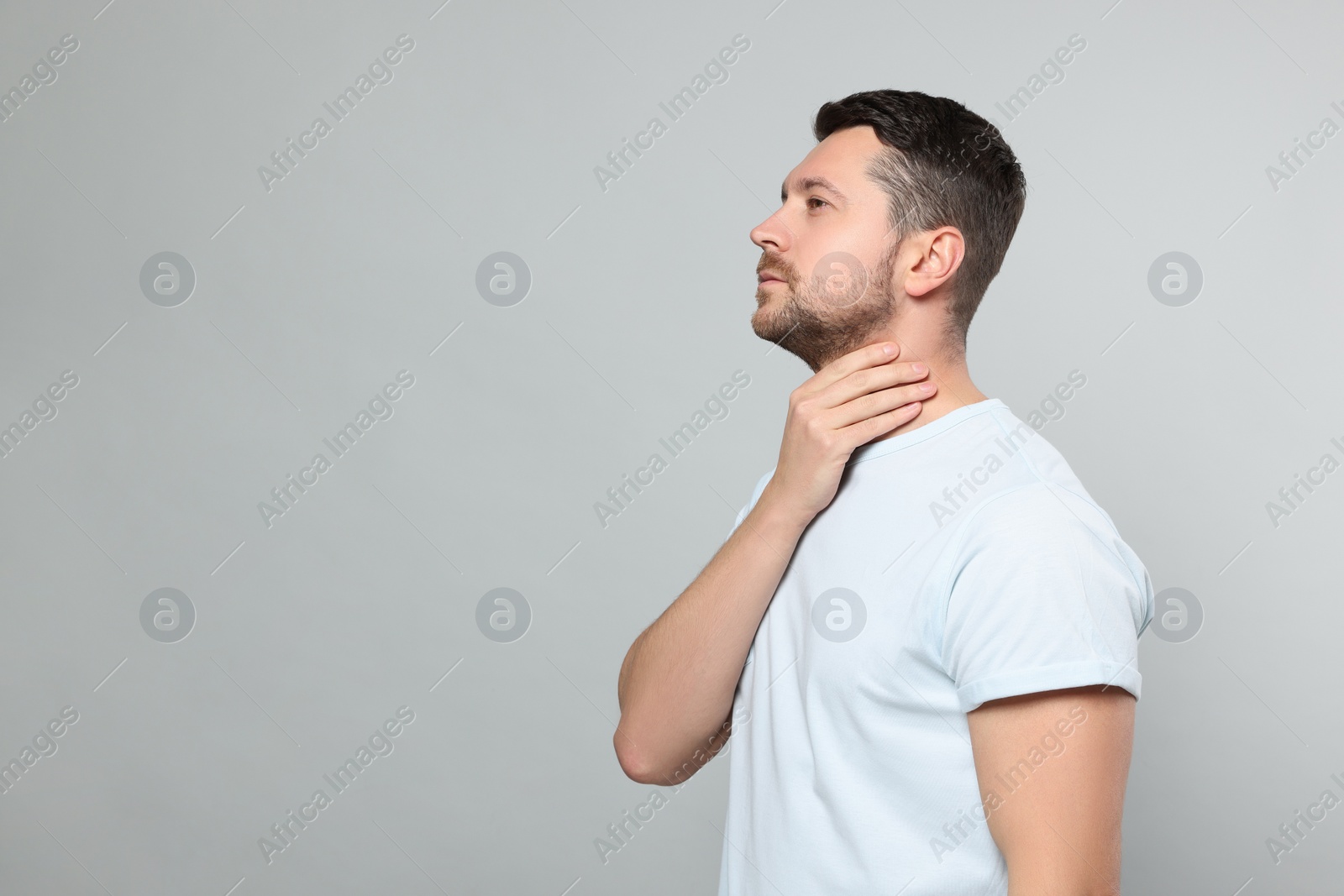 Photo of Man suffering from sore throat on light gray background, space for text