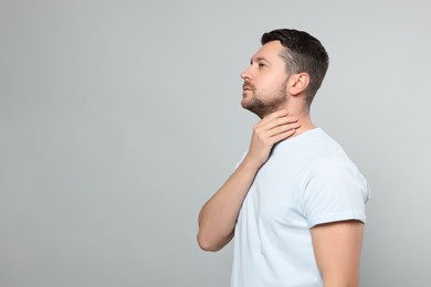 Photo of Man suffering from sore throat on light gray background, space for text