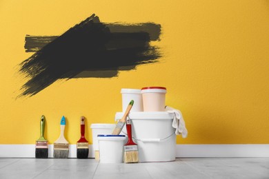 Set with decorator's tools and paint on floor near yellow wall