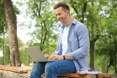 Photo of Young man in stylish outfit with laptop outdoors