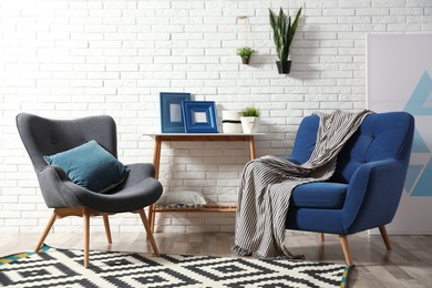 Photo of Modern interior with cozy armchairs and table near brick wall