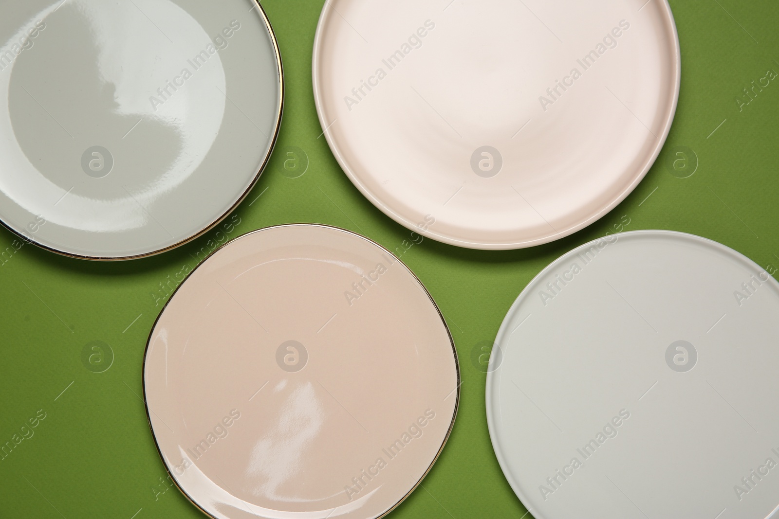 Photo of Beautiful ceramic plates on green background, top view