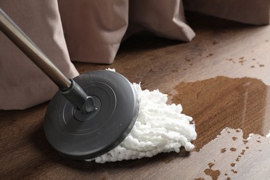 Photo of Cleaning dirty parquet floor with mop, closeup