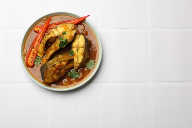 Photo of Tasty fish curry on white tiled table, top view. Space for text. Indian cuisine