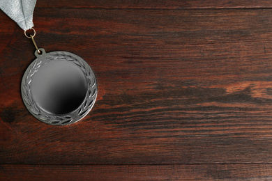 Photo of Silver medal on wooden background, top view. Space for design