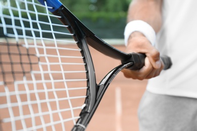 Photo of Sportsman with racket at tennis court, closeup
