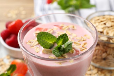 Photo of Glass of tasty berry smoothie with oatmeal on table, closeup