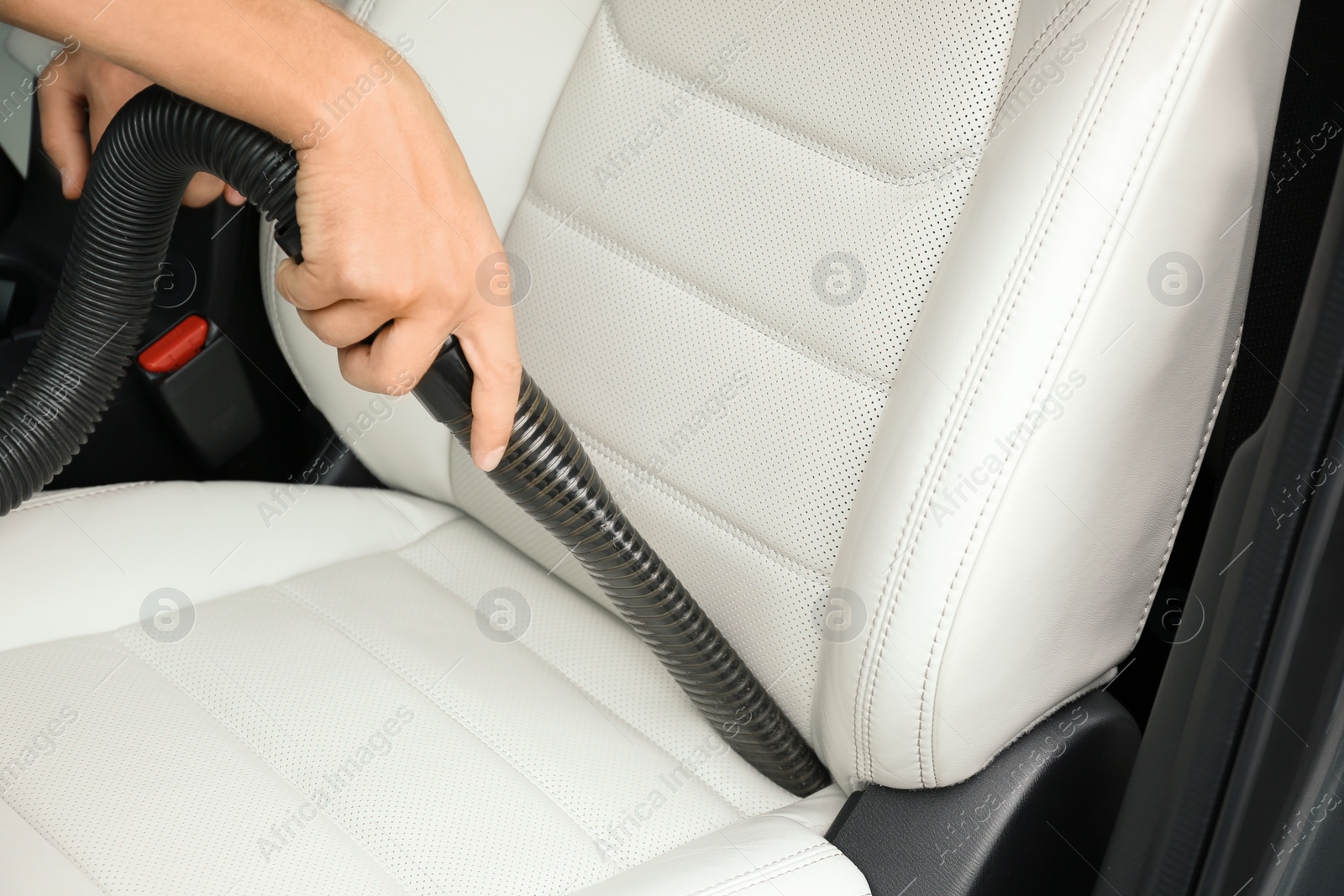 Photo of Man using vacuum cleaner in auto, closeup. Car wash