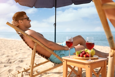 Photo of Happy man resting on sunny beach at resort