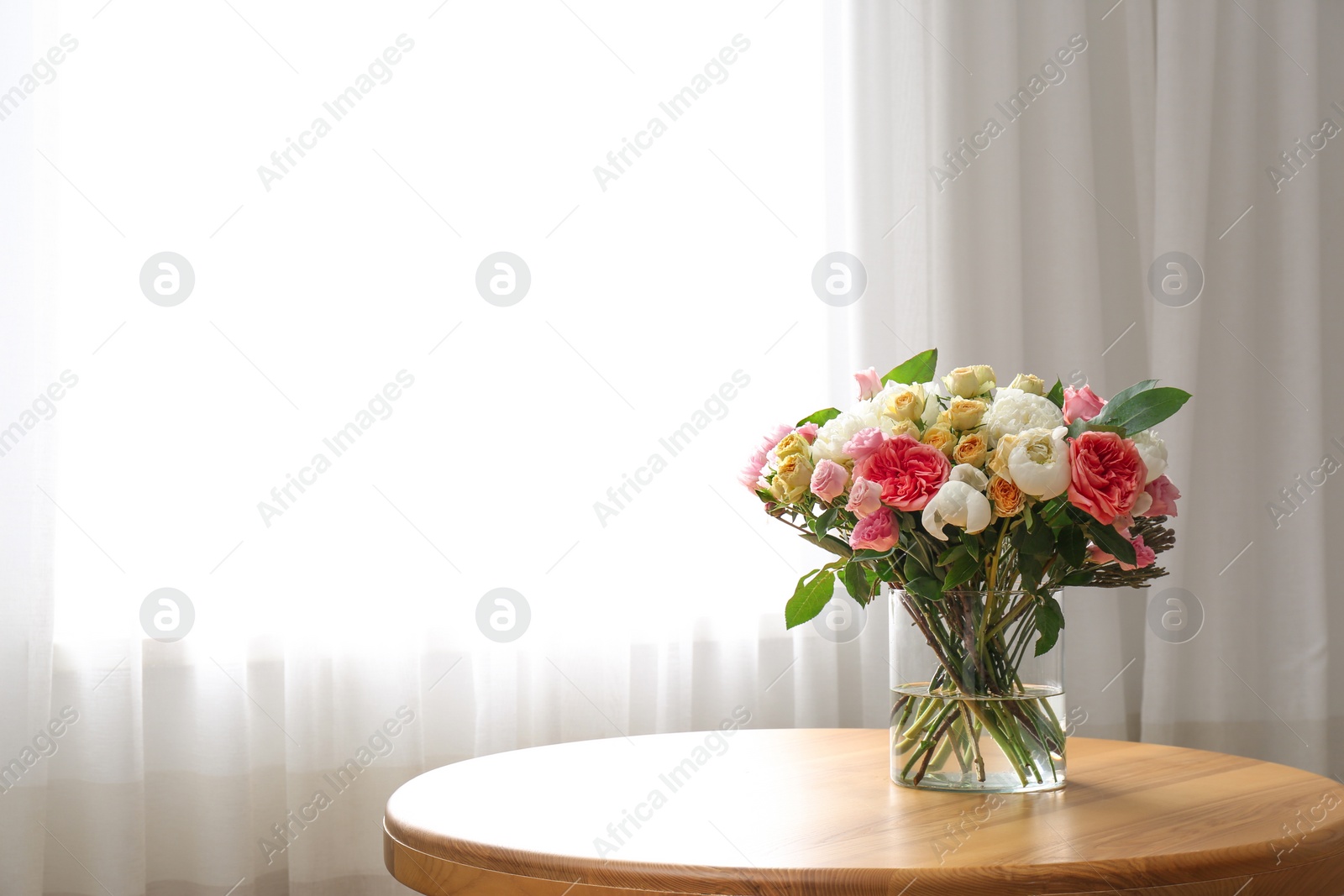 Photo of Beautiful flower bouquet in vase on table near window at home. Space for text