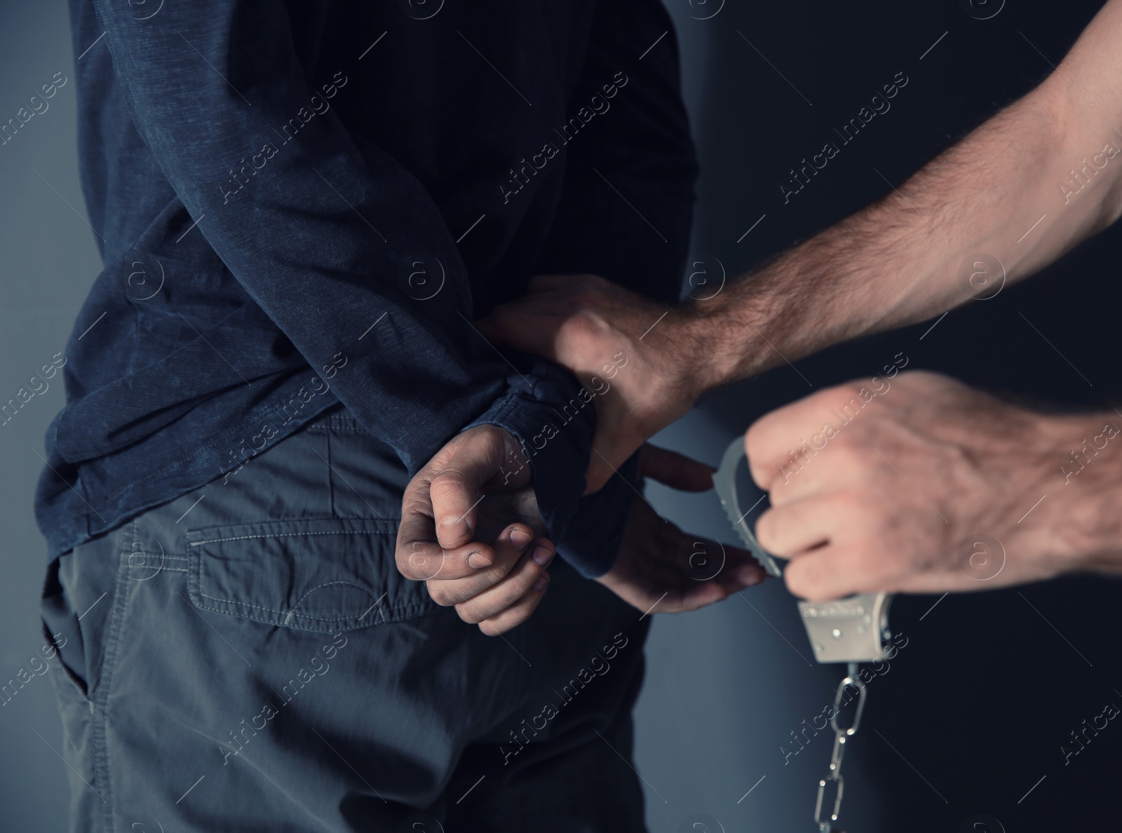 Photo of Man putting handcuffs on drug dealer, closeup view