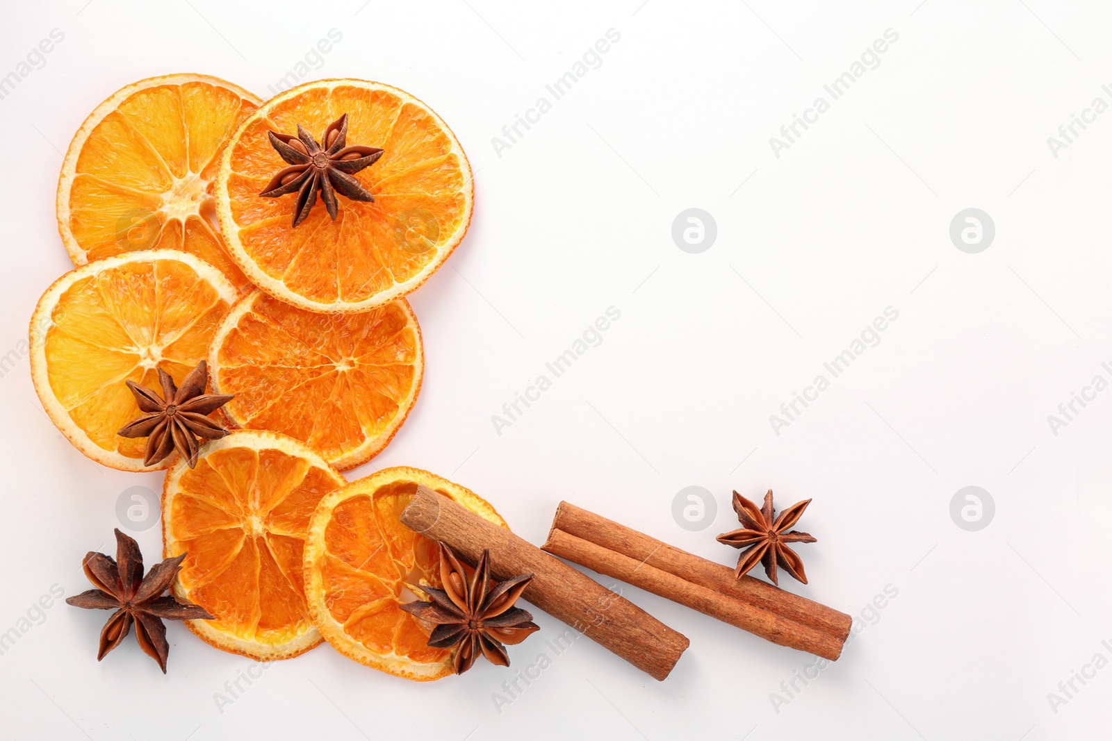 Photo of Flat lay composition with dry orange slices, anise stars and cinnamon sticks on white background. Space for text