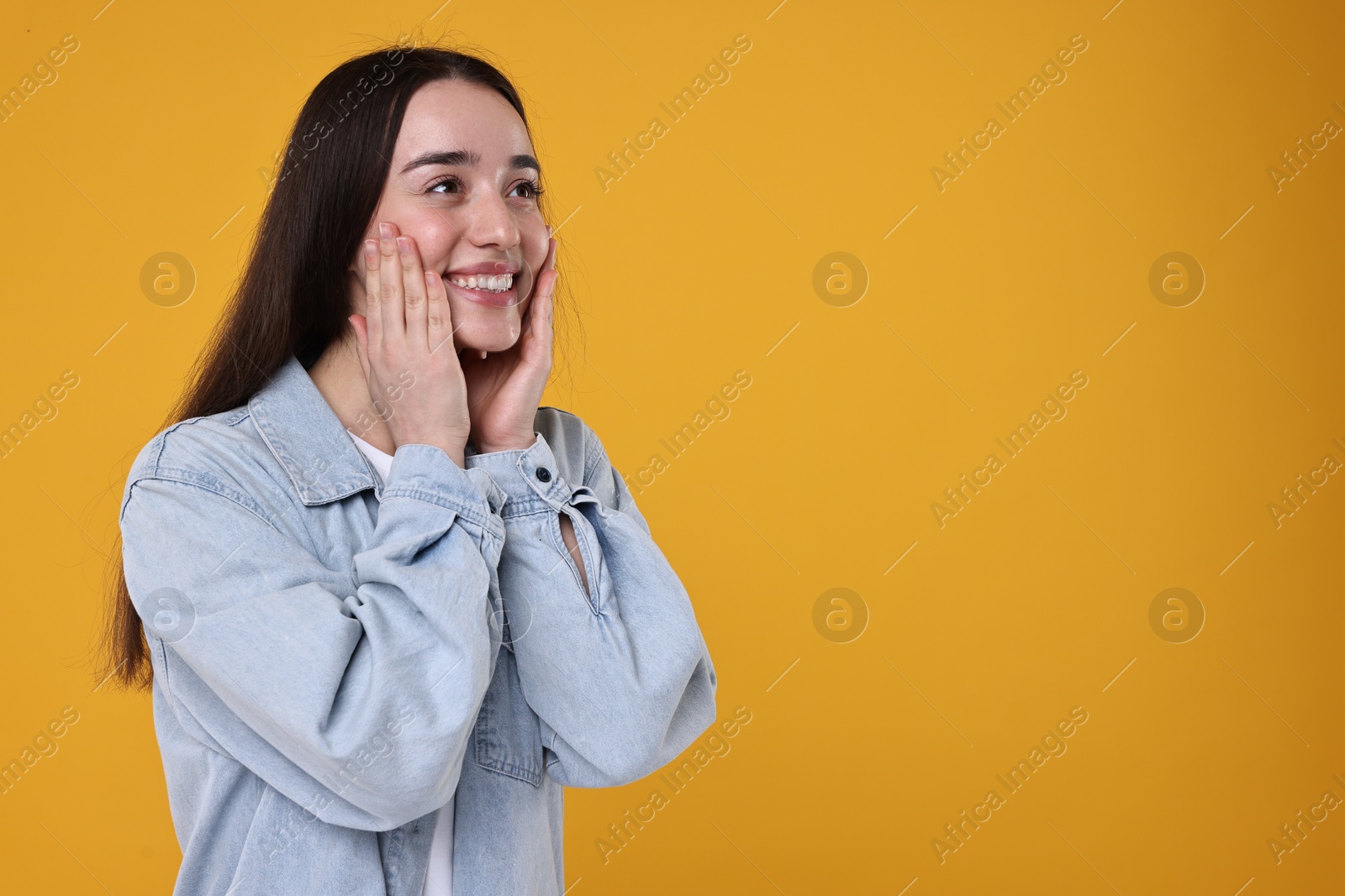 Photo of Portrait of happy surprised woman on orange background. Space for text