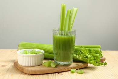 Glass of celery juice and fresh vegetables on wooden table