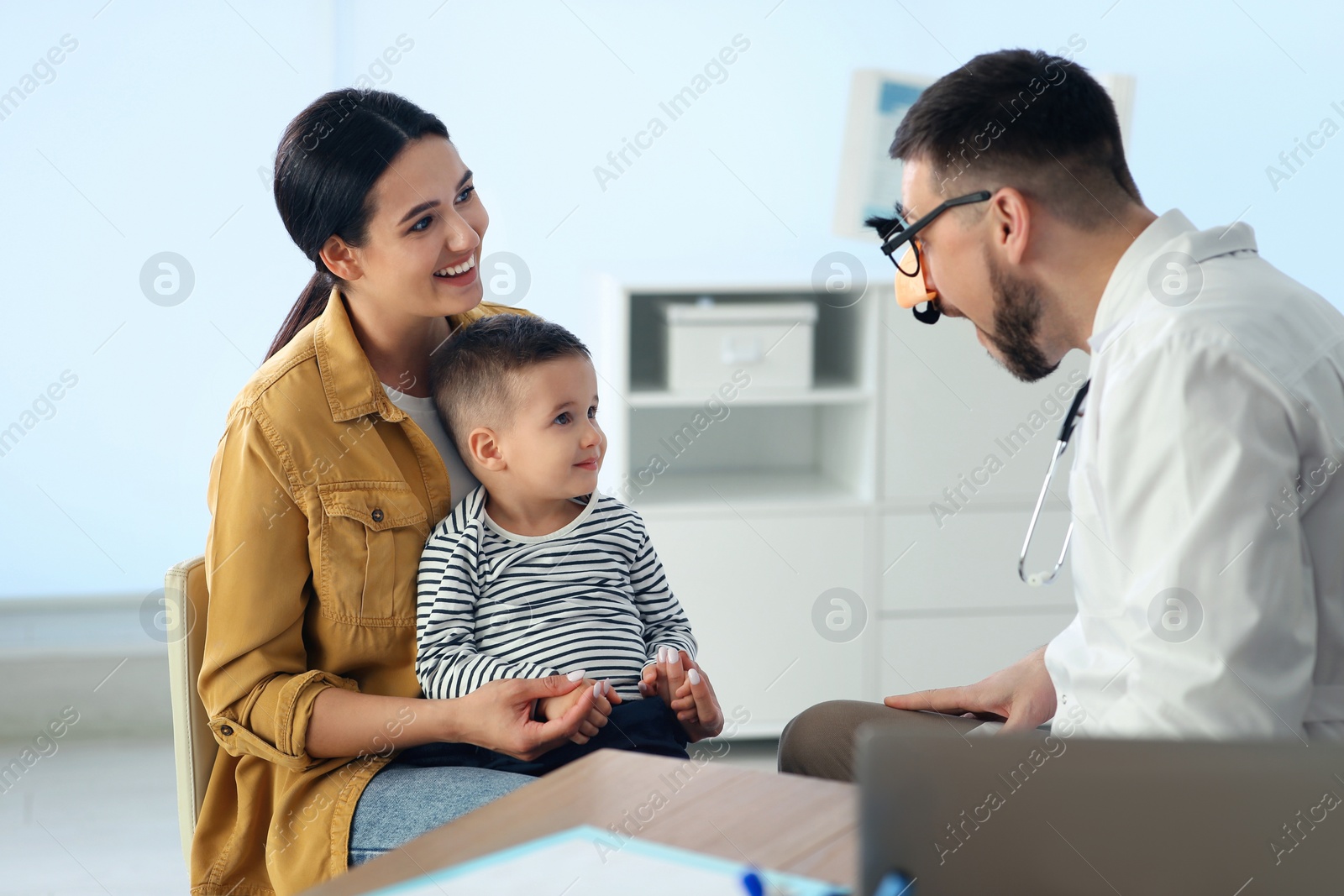 Photo of Mother and son visiting pediatrician in hospital. Doctor playing with little boy