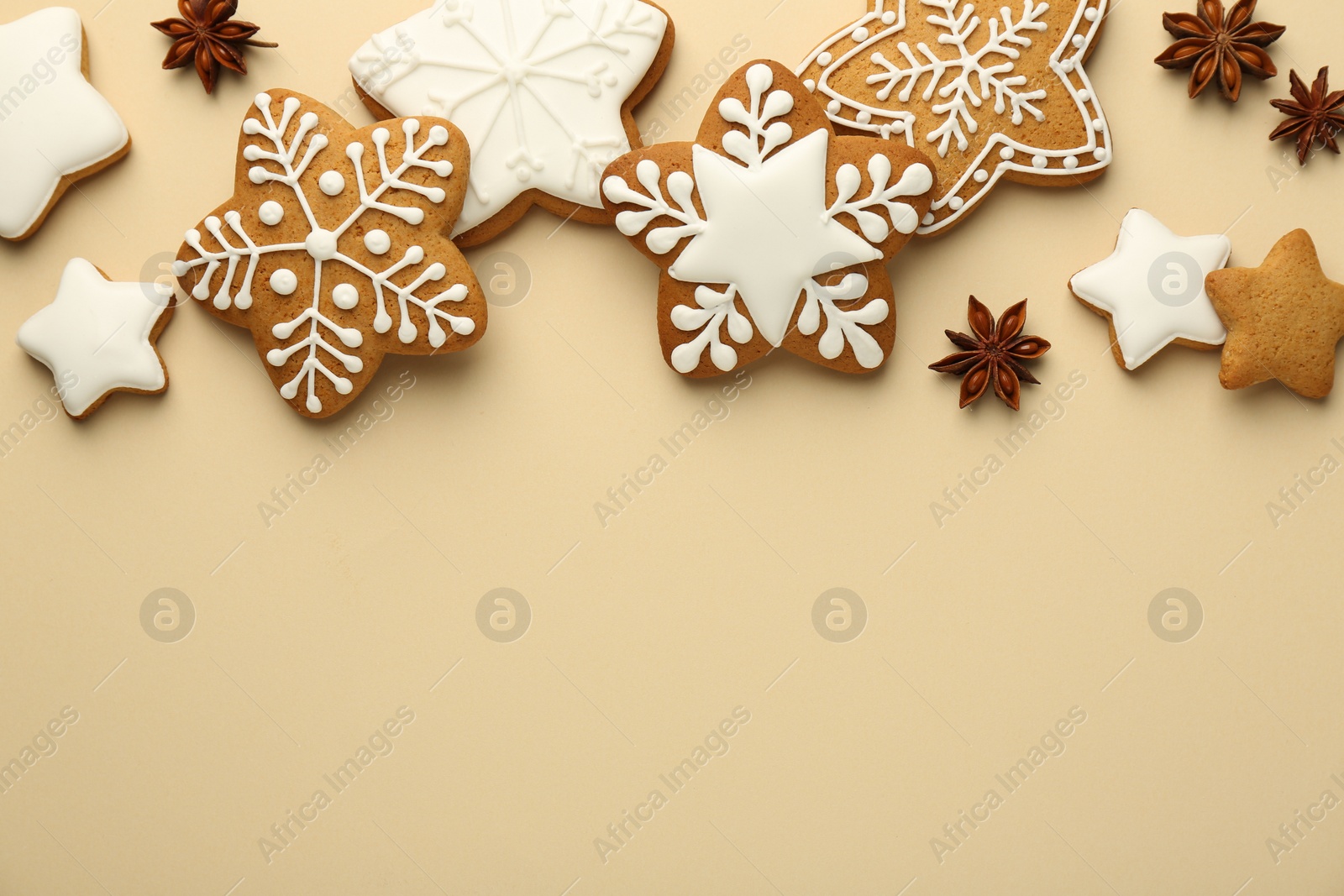 Photo of Tasty Christmas cookies with icing and anise stars on beige background, flat lay. Space for text