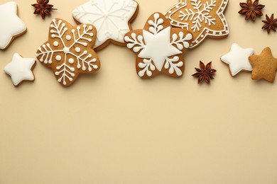 Photo of Tasty Christmas cookies with icing and anise stars on beige background, flat lay. Space for text