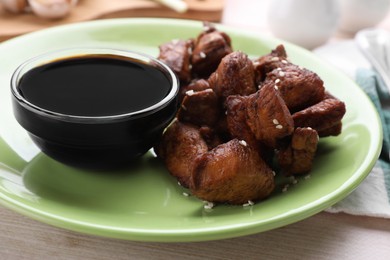 Tasty roasted meat served with soy sauce on table, closeup