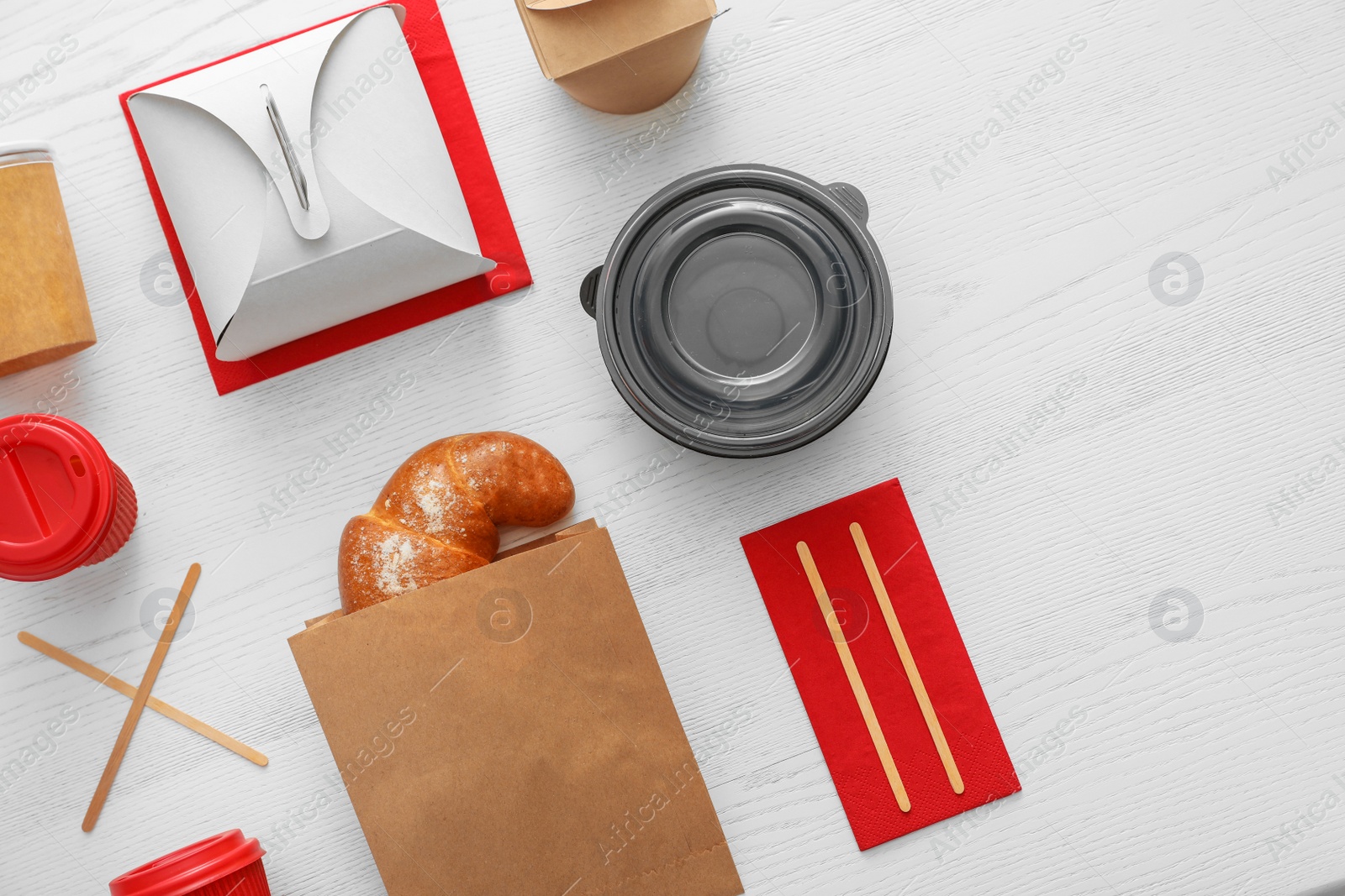 Photo of Flat lay composition with paper bag and different takeaway items on wooden background. Space for design