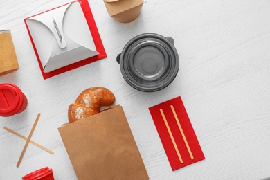 Photo of Flat lay composition with paper bag and different takeaway items on wooden background. Space for design