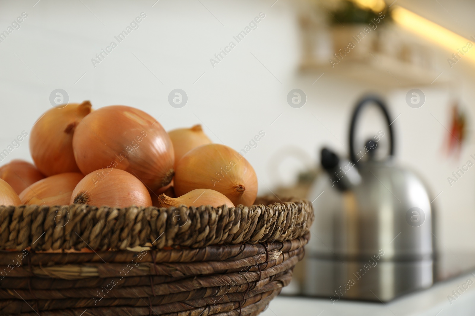 Photo of Basket with fresh onions in modern kitchen, closeup. Space for text