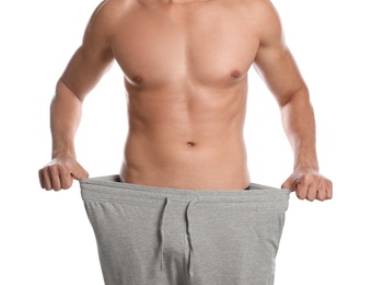 Photo of Young man with slim body in old big size pants on white background, closeup view