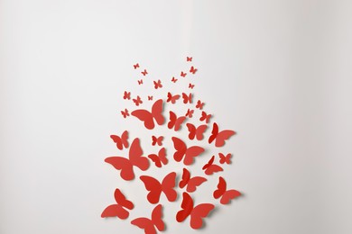 Bright red paper butterflies on white wall