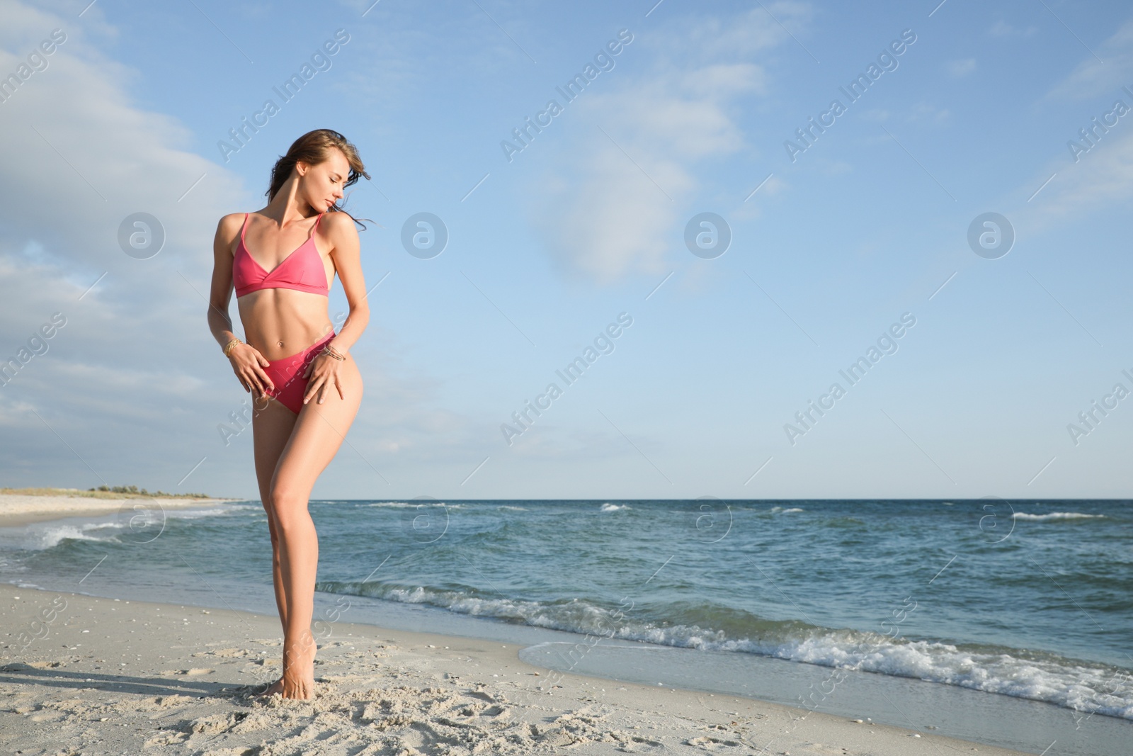 Photo of Attractive woman with beautiful body in bikini on sand near sea. Space for text