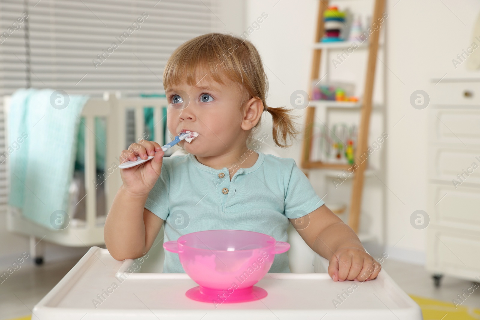 Photo of Cute little child eating tasty yogurt with spoon at home