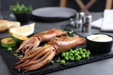 Photo of Tasty grilled squids served on black table, closeup