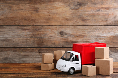 Photo of Truck model and carton boxes on wooden background, space for text. Courier service