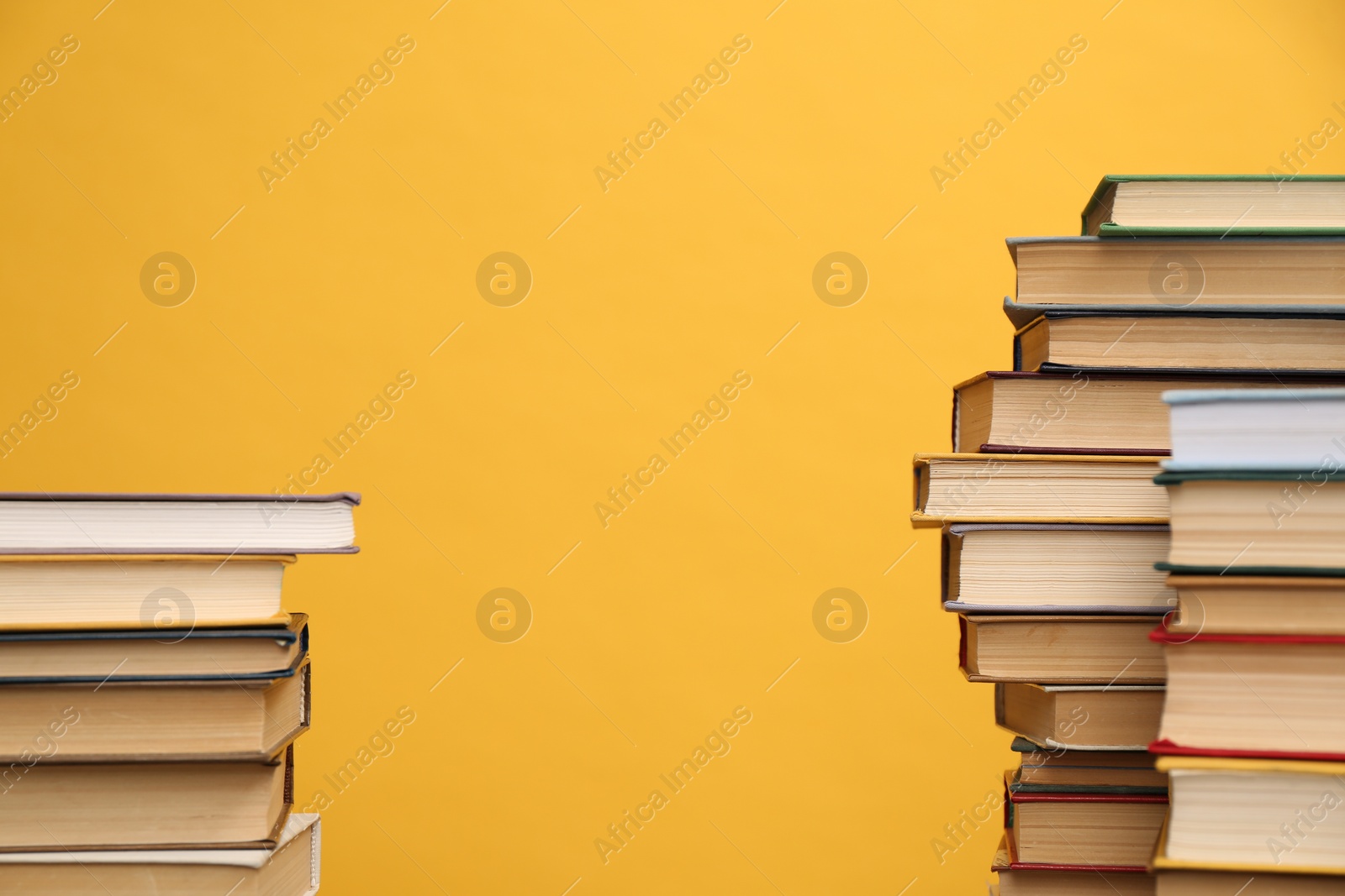 Photo of Many hardcover books on orange background, space for text. Library material